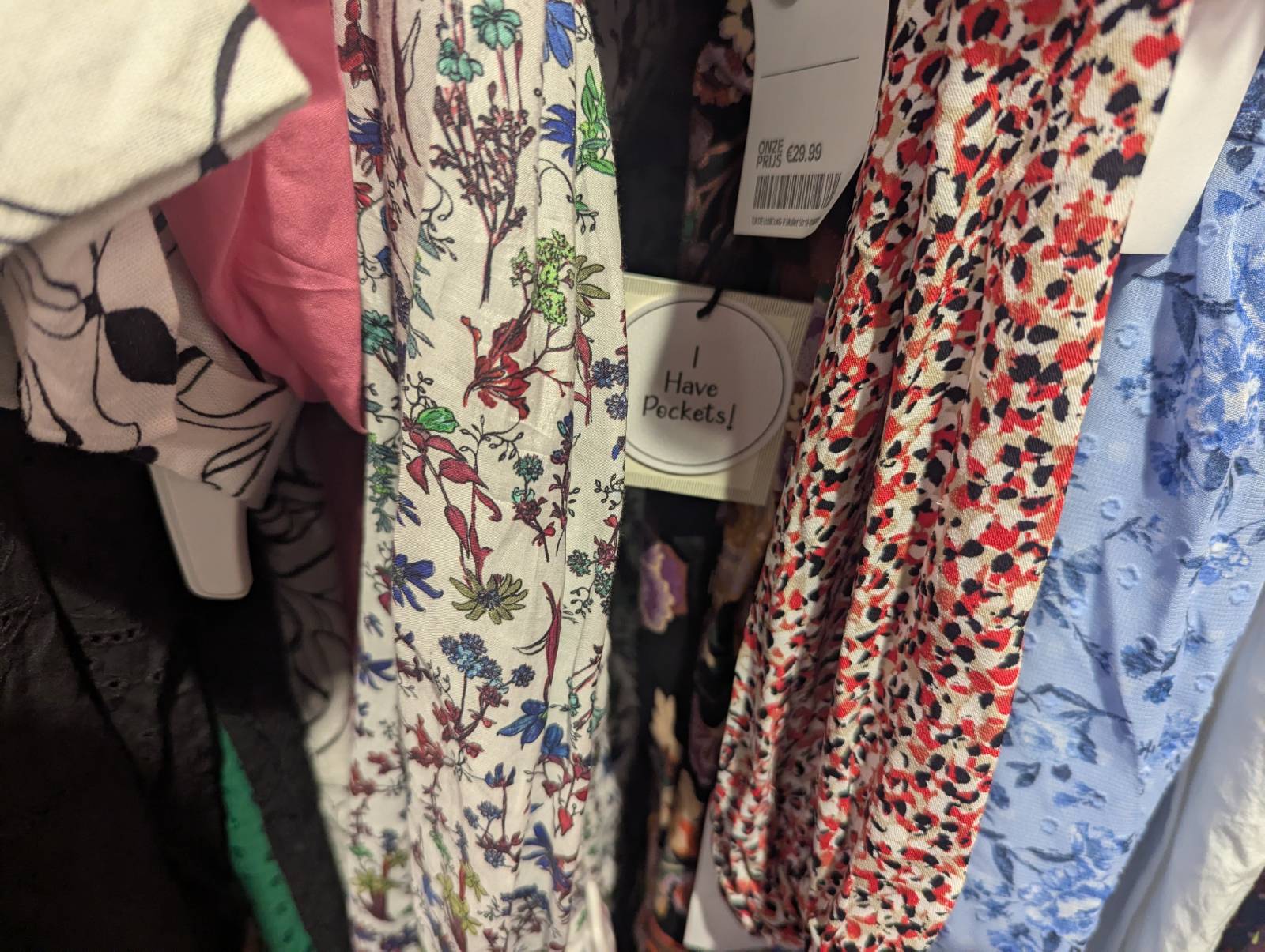 Colorful patterned clothes on a rack with a tag reading "I Have Pockets!" 